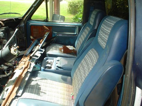 1981 Ford Bronco - The interior of a 1981 Ford Bronco shows blue seats and a heavily damaged dashboard.