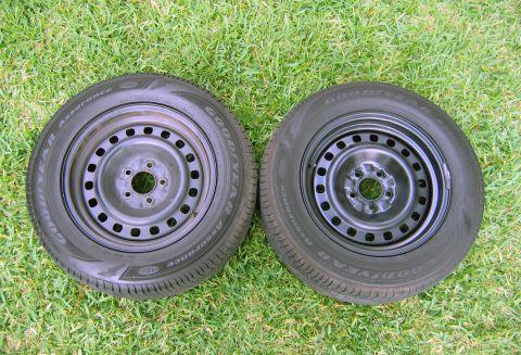 2000 Ford Crown Victoria - Two steel wheels with Goodyear Assurance tires are displayed on a grassy surface.