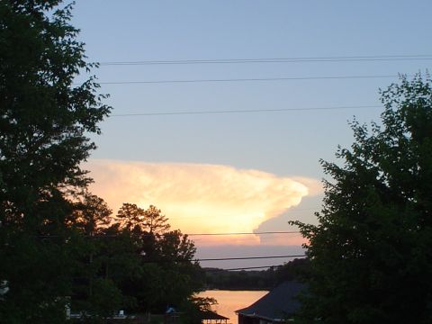 1981 Ford Bronco - A dramatic cloud formation glows in the sky at sunset, seen over a lake and trees.