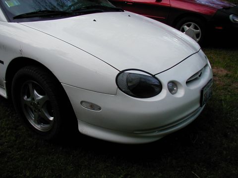 1997 Ford Taurus - Front view of a white 1997 Ford Taurus parked next to a red vehicle.