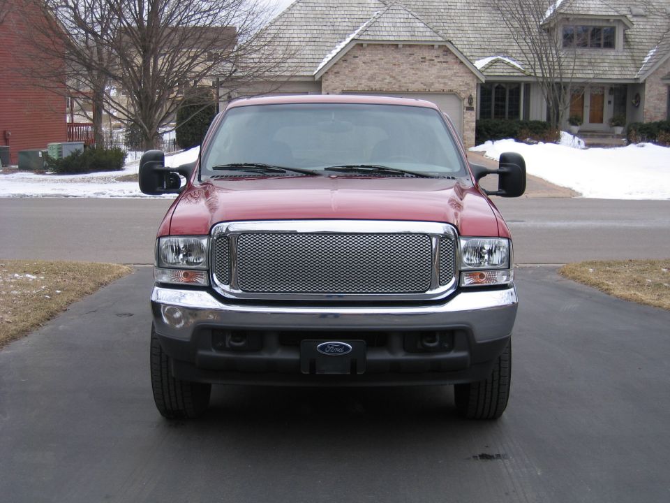 Front view of a red Ford Excursion with chrome mesh grille on a driveway