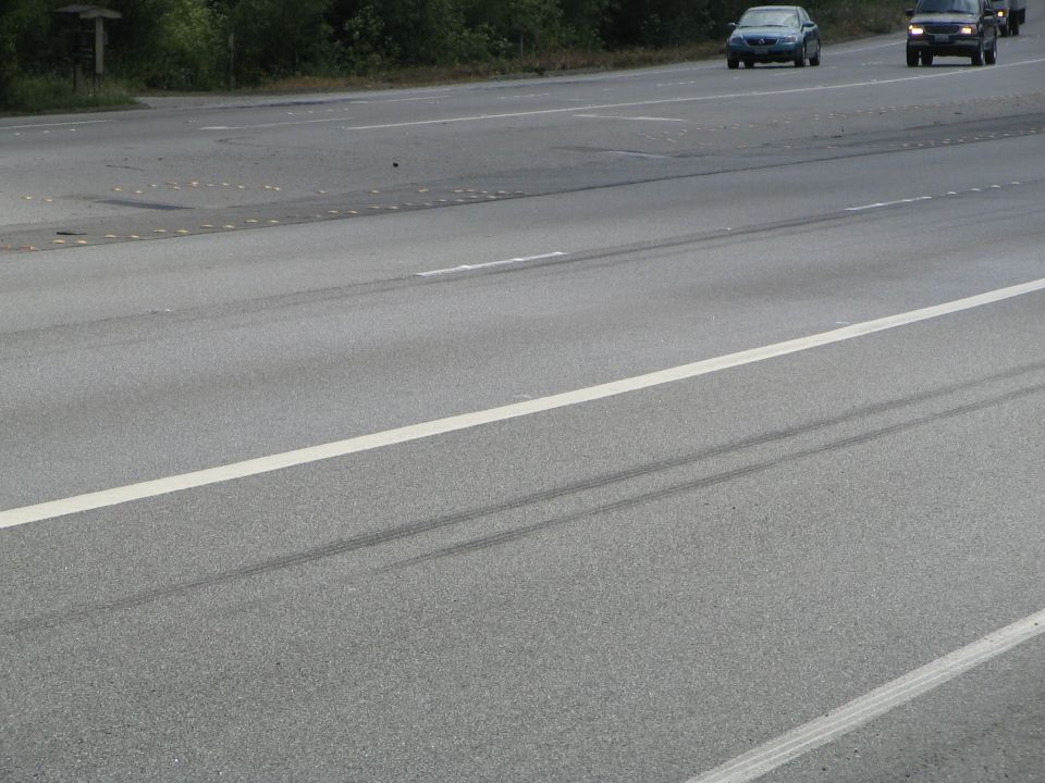 Highway scene with tire marks on the asphalt and two cars driving in the distance