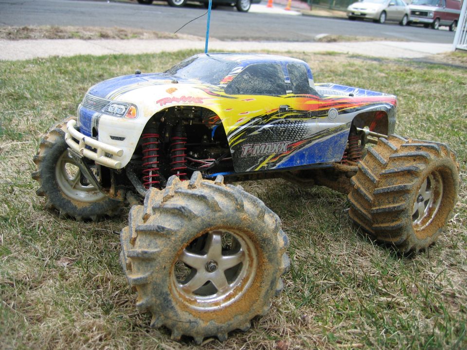 Mud-covered Traxxas T-MAXX radio-controlled monster truck sitting on dry grass