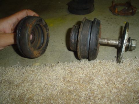 1993 Ford Taurus - Two rubber suspension components, likely from a vehicle's subframe, are shown. One is held in a hand, while the other is attached to a bolt.