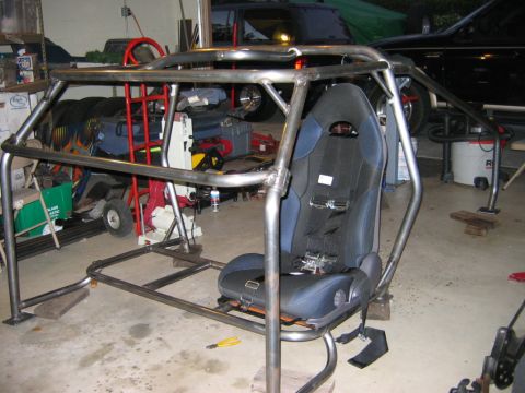 1985 Ford Bronco - Custom roll cage and racing seat assembly in a garage.