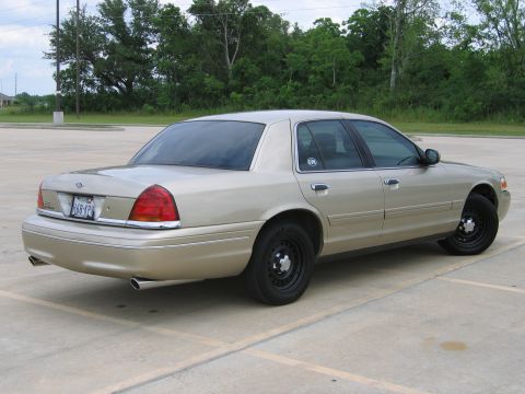 2000 Ford Crown Victoria - This 2000 Ford Crown Victoria is shown in a rear three-quarter view, highlighting its tan exterior and black steel wheels.
