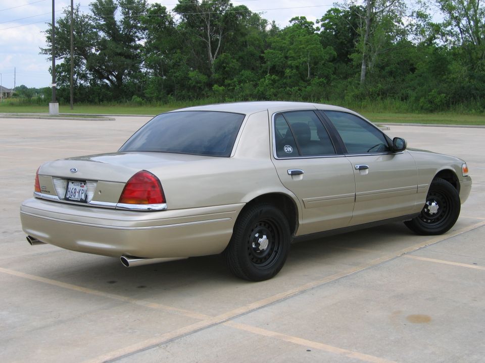Tan 2000 Ford Crown Victoria, rear quarter view with black steel wheels