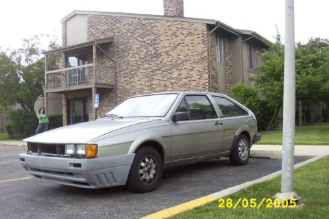 1983 Volkswagen Scirocco - A silver 1983 Volkswagen Scirocco is parked outside a brick building, showing its front end with the bumper removed.