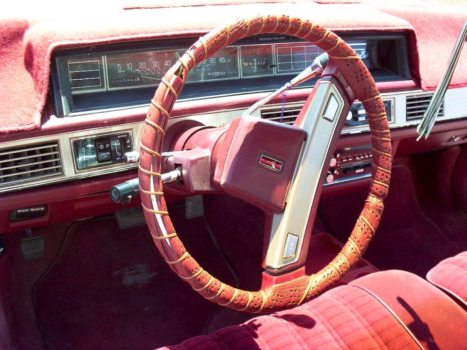 Red interior with lace-wrapped steering wheel, column shifter and analog speedometer reading to 85