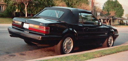 1985 Ford Mustang - Rear view of a black 1985 Ford Mustang convertible parked on a residential street.