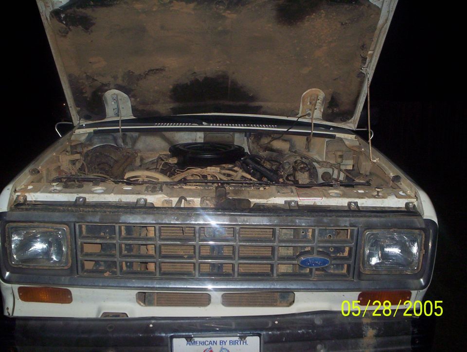 1984 Ford Bronco II engine bay with hood open. Grille has horizontal bars and a blue Ford oval emblem