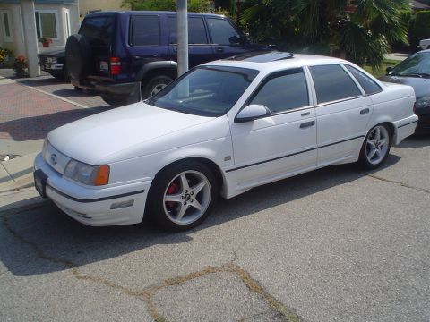 1993 Ford Taurus - White 1993 Ford Taurus sedan with aftermarket wheels and red brake calipers.