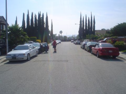 1993 Ford Taurus - A residential street is lined with parked cars under a clear sky.
