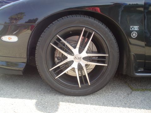 1993 Ford Taurus - Close-up of a black car's wheel and fender, showing a V8 badge.
