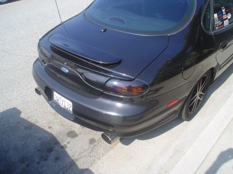 1993 Ford Taurus - Rear view of a black 1993 Ford Taurus, a custom spoiler and tinted taillights.