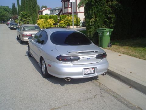 1993 Ford Taurus - This silver sedan, likely a 1996 model, is parked on a street with another car visible.