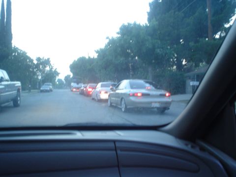 1993 Ford Taurus - A line of cars is stopped on a residential street during the day.