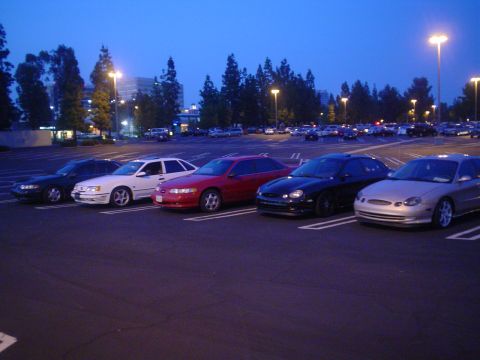 1993 Ford Taurus - A silver 1996 Ford Taurus is parked in a lot with several other vehicles at dusk.