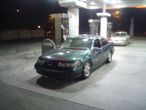 1993 Ford Taurus - A green 1993 Ford Taurus is parked at a gas station at night, with another car visible in the background.