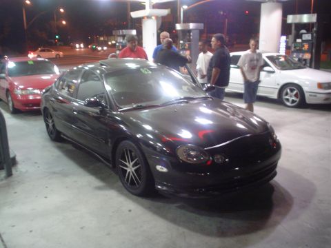 1993 Ford Taurus - A black Ford Taurus is parked at a gas station with other vehicles.