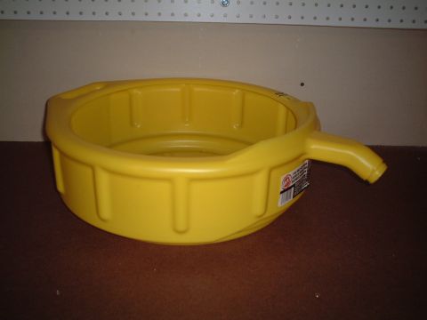 2000 Ford Excursion - A yellow oil drain pan sits on a brown surface with a pegboard wall in the background.