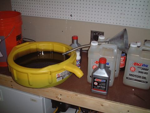 2000 Ford Excursion - Supplies for an oil change are laid out on a workbench, including a drain pan and various AMSOIL products.