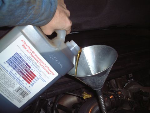2000 Ford Excursion - Oil change in progress, pouring new oil into the engine via a funnel.