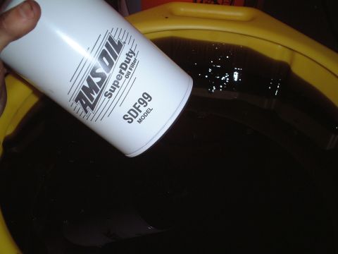 2000 Ford Excursion - An AMSOIL SuperDuty Oil Filter, model SDF99, is shown above a drain pan containing used engine oil.