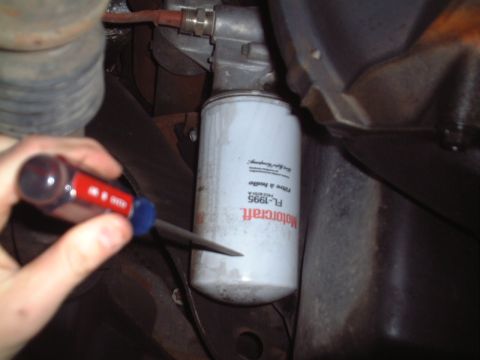 2000 Ford Excursion - A Motorcraft FL-1995 oil filter is visible, with a screwdriver poised to loosen it.