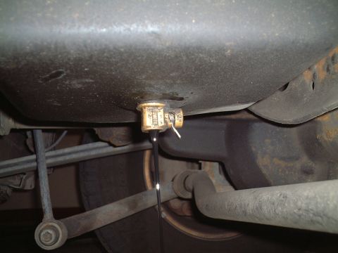 2000 Ford Excursion - Oil is draining from the vehicle's oil pan through a quick-release drain plug.