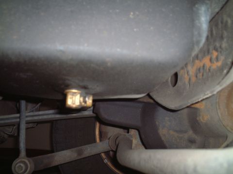 2000 Ford Excursion - Close-up view of the oil drain plug on the underside of a vehicle.