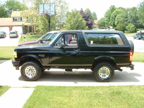 1994 Ford Bronco - A black Ford Bronco is parked in a suburban driveway on a sunny day.