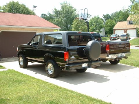 1994 Ford Bronco - A black Ford Bronco is parked in a driveway next to a maroon Ford F-150.