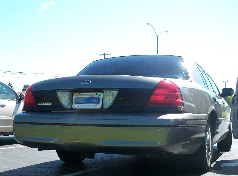Rear of a gray Ford Crown Victoria with Police Interceptor trunk badge in a parking lot