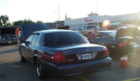 1998 Ford Crown Victoria - Rear view of a 1998 Ford Crown Victoria at a car meet with multiple vehicles present.