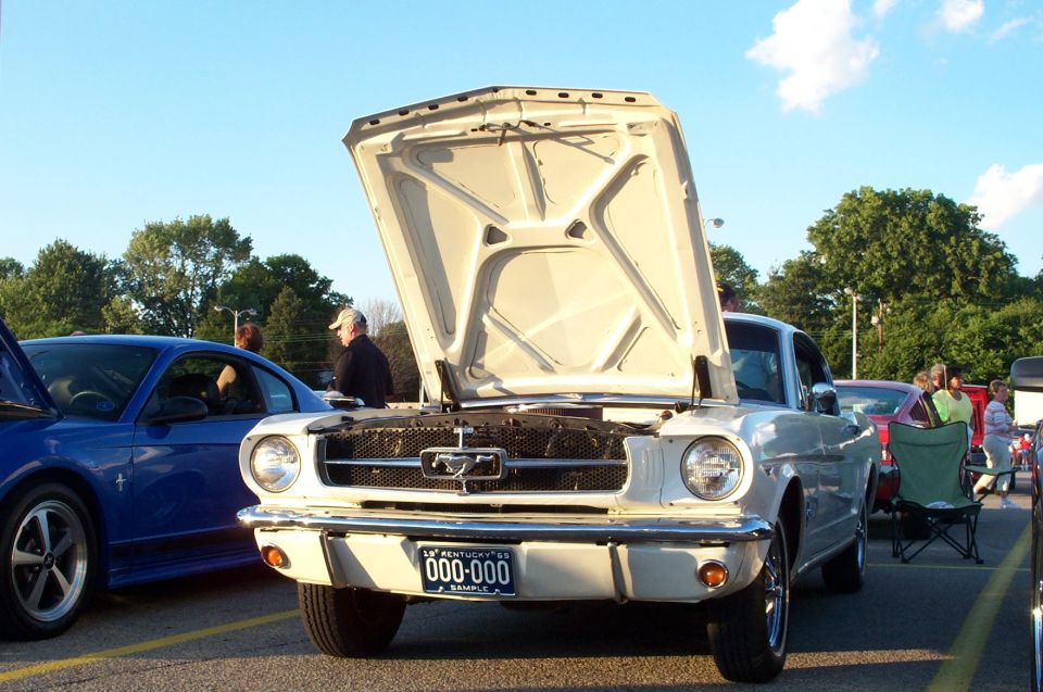 White early Ford Mustang coupe with hood up at a car show, front view