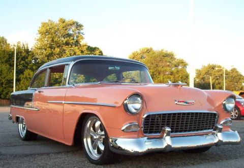1998 Ford Crown Victoria - A classic pink and black Chevrolet sedan from 1955 is displayed at a car cruise.