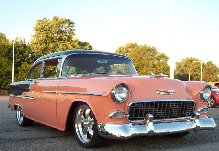 Salmon and black 1955 Chevrolet two-door with chrome grille and polished five-spoke wheels