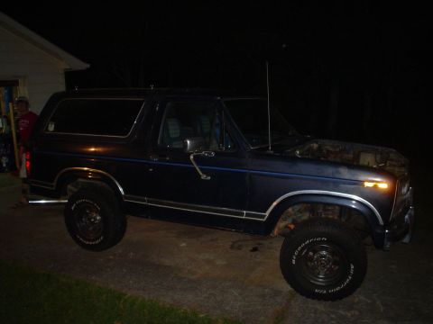 1981 Ford Bronco - 1981 Ford Bronco parked outside a house at night with the hood open.