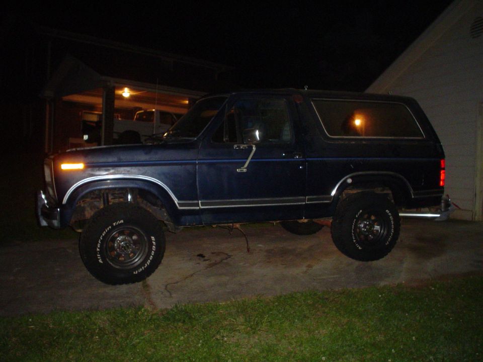 Blue Ford Bronco parked outside at night. Tires say BFGoodrich All-Terrain T/A