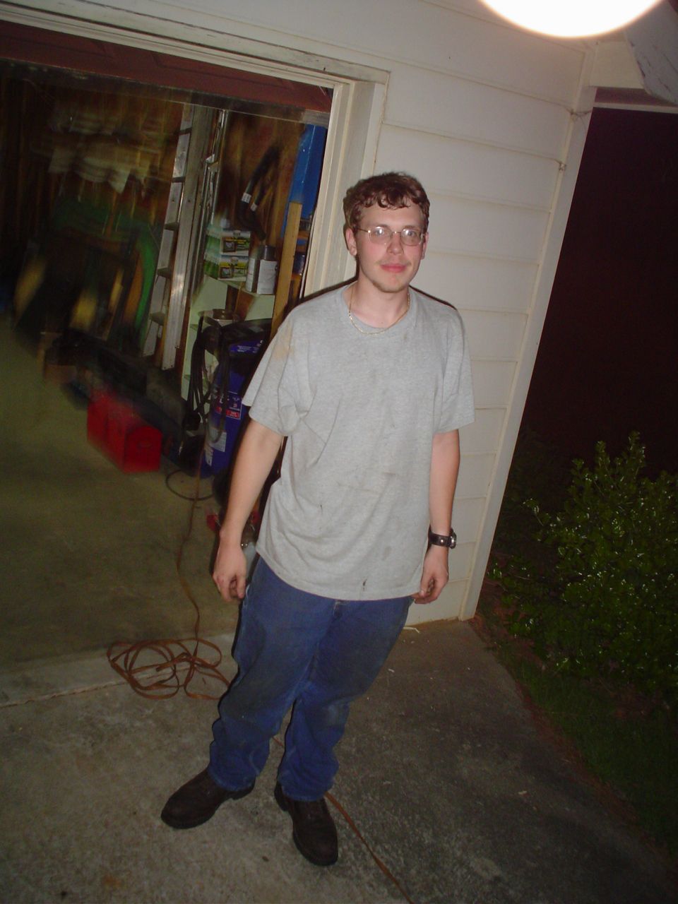 Man in t-shirt and jeans standing in front of an open garage door