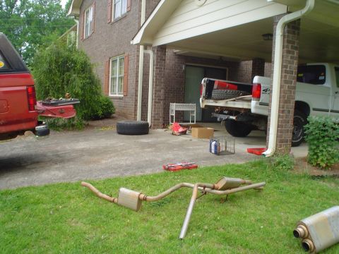 1981 Ford Bronco - A red pickup truck and a white pickup truck are parked in a driveway with a removed exhaust system on the lawn.