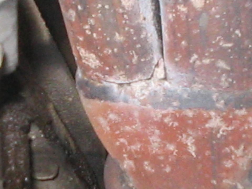 Close-up of a corroded red radiator hose with a cracked seam and white residue