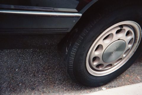 1985 Ford Mustang - A close-up view of a car's wheel, showing the tire and a hubcap with the Ford logo.