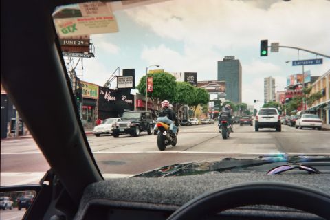 1990 Ford Bronco - Motorcycles and cars travel a busy city boulevard near Larrabee Street, with the Viper Room and shop signs lining the road.