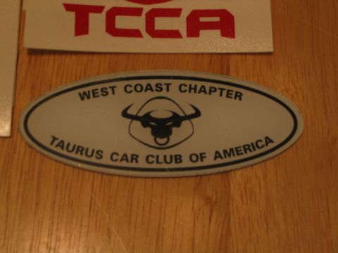2002 Ford Taurus - A sticker for the Taurus Car Club of America is shown on a wooden background.