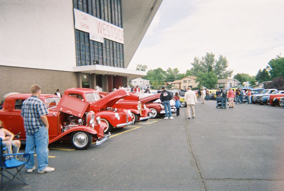 Row of red 1930s hot rods with open hoods at an outdoor car show