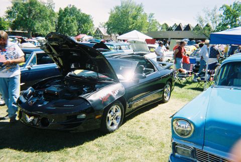 1972 Ford Ranchero - Black Pontiac Firebird displayed at a car show with its hood up, next to a blue classic car.