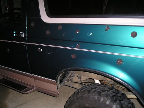 1996 Ford Bronco - This 1996 Ford Bronco exhibits numerous circular dents along its side, contrasting with its teal and brown two-tone paint scheme.