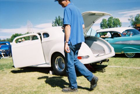1972 Ford Ranchero - A man walks past a white coupe with its doors and trunk open at a car show.